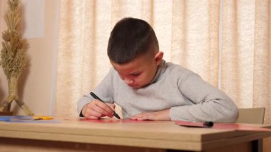 Bir çocuk renkli kartondan bir zanaat yapıyor. Hobiler ve eğlence..