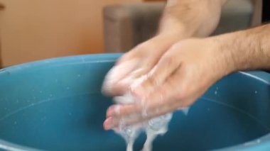 Beyaz çorapları havuzda elle yıkayan bir adam. Ev işleri..