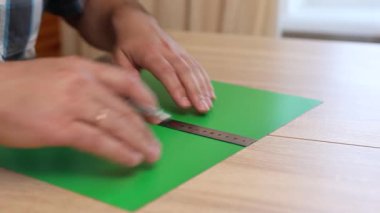 Renkli karton üzerine kesme çizgileri çizen eller, kağıt modeli için el yapımı şablon, DIY proje hazırlığı.