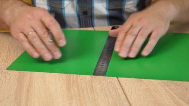 Renkli karton üzerine kesme çizgileri çizen eller, kağıt modeli için el yapımı şablon, DIY proje hazırlığı.