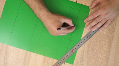 Renkli karton üzerine kesme çizgileri çizen eller, kağıt modeli için el yapımı şablon, DIY proje hazırlığı.