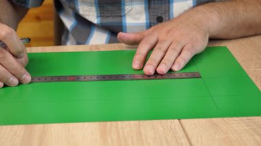 Renkli karton üzerine kesme çizgileri çizen eller, kağıt modeli için el yapımı şablon, DIY proje hazırlığı.