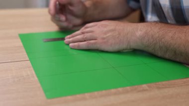 Renkli karton üzerine kesme çizgileri çizen eller, kağıt modeli için el yapımı şablon, DIY proje hazırlığı.