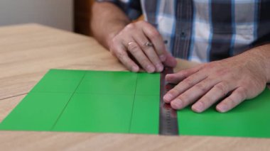 Renkli karton üzerine kesme çizgileri çizen eller, kağıt modeli için el yapımı şablon, DIY proje hazırlığı.