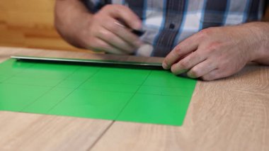 Renkli karton üzerine kesme çizgileri çizen eller, kağıt modeli için el yapımı şablon, DIY proje hazırlığı.