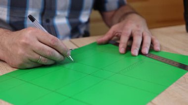 Renkli karton üzerine kesme çizgileri çizen eller, kağıt modeli için el yapımı şablon, DIY proje hazırlığı.