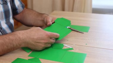 Eller karton kesikleri katlıyor ve yapıştırıyor, yaratıcı DIY zanaat projesi için kağıt modelinin parçalarını birleştiriyor.