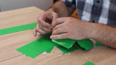 Eller karton kesikleri katlıyor ve yapıştırıyor, yaratıcı DIY zanaat projesi için kağıt modelinin parçalarını birleştiriyor.