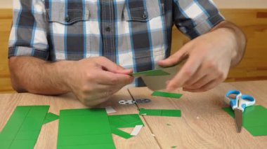 Eller karton kesikleri katlıyor ve yapıştırıyor, yaratıcı DIY zanaat projesi için kağıt modelinin parçalarını birleştiriyor.
