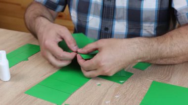 Eller karton kesikleri katlıyor ve yapıştırıyor, yaratıcı DIY zanaat projesi için kağıt modelinin parçalarını birleştiriyor.