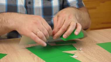 Eller karton kesikleri katlıyor ve yapıştırıyor, yaratıcı DIY zanaat projesi için kağıt modelinin parçalarını birleştiriyor.