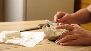 Süzme peynir, şeffaf bir kasede kaşıkla ekşi kremayla karıştırılır..