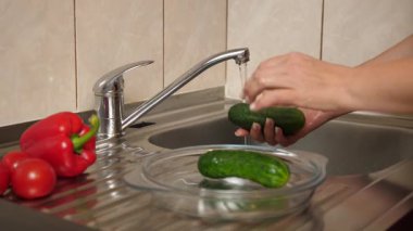 Akan suyun altında biber ve salatalık yıkamak. Sebze yemekleri hazırlanıyor..