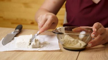 Süzme peynir, şeffaf bir kasede kaşıkla ekşi kremayla karıştırılır..