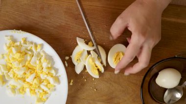 Haşlanmış yumurta bir bıçakla parçalara ayrıldı. Yumurtalı yemek yapmak..