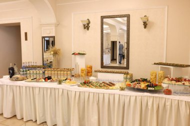 Lvivske birası, kanepeler ve aperatiflerle dolu geniş bir ziyafet masası; şenlikli bir misafir resepsiyonu hazırlığı. Salonda..