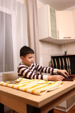 Oğlan çatal ve mutfak bıçaklarını siliyor. Ev işleri..