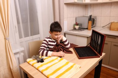 Oğlan çatal ve mutfak bıçaklarını siliyor. Ev işleri..