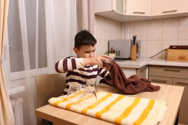 Oğlan bardakları ve bardakları havluyla siler. Ev işleri..