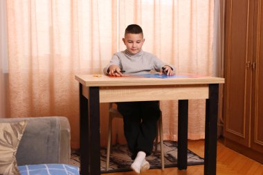 Bir çocuk masada otururken renkli kağıtlardan başvuru yapıyor. Yaratıcılık ve eğlence kavramı.