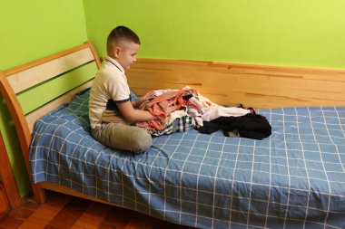 Çocuk elbiselerini yıkadıktan sonra dikkatlice katlar..