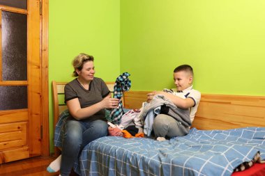 Bir çocuk yıkadıktan sonra annesinin elbiselerini katlamasına yardım eder..