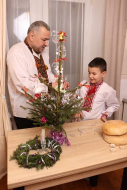 Ukrayna nakış işindeki bir adam ve oğlu Noel ağacı süslemişler..