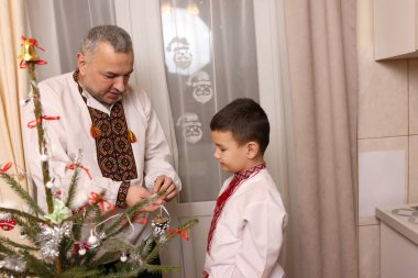 Ukrayna nakış işindeki bir adam ve oğlu Noel ağacı süslemişler..