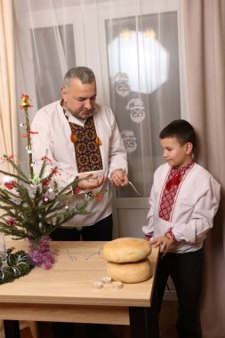 Ukrayna nakış işindeki bir adam ve oğlu Noel ağacı süslemişler..