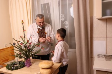 Ukrayna nakış işindeki bir adam ve oğlu Noel ağacı süslemişler..