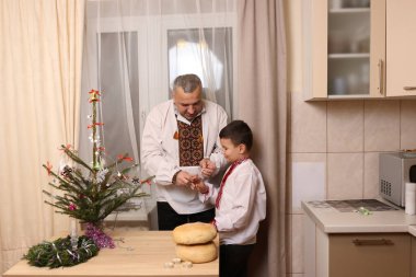 Ukrayna nakış işindeki bir adam ve oğlu Noel ağacı süslemişler..