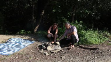 Erkek ve kadın dışarıda barbekü hazırlamak için ateş yakıyor. Açık havada piknik..