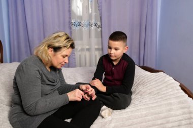 Anne, oğullarının tırnaklarını kesmeye, bakım ve konforunu göstermeye odaklanmış.