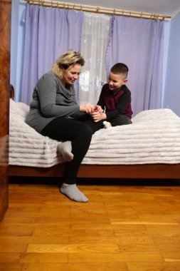 Anne, oğullarının tırnaklarını kesmeye, bakım ve konforunu göstermeye odaklanmış.