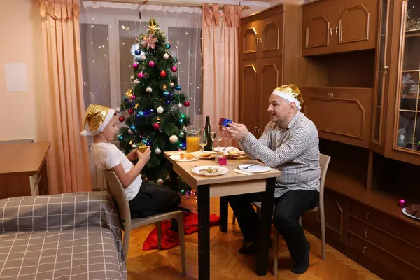 Baba oğul Noel 'i ya da yeni yılı bir şenlik masasında kutluyorlar.