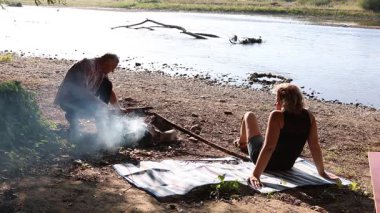 Erkek ve kadın dışarıda barbekü hazırlamak için ateş yakıyor. Açık havada piknik..