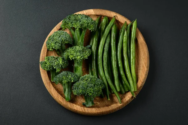 Brokoli ve yeşil fasulyeler ahşap bir kasede. Darl arkaplanda brokoli izole edildi