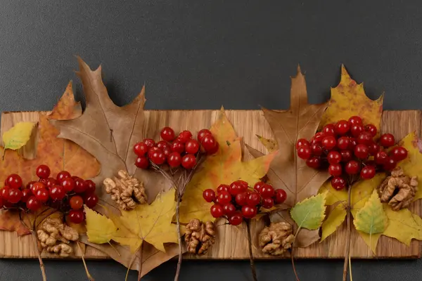 stock image Autumn leaves and guelder rose on wooden background