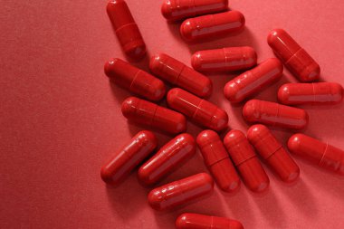 Kırmızı kapsüller ya da kırmızı arka plana saçılmış haplar, ilaç haplarının üst görünümü