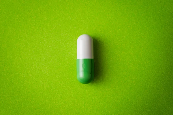 Renkli farklı haplar ve sarı yüzeyde tıbbi termometre.