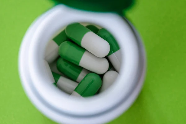 Beyaz kap görüntüsünde yeşil ve beyaz haplar veya kapsüller