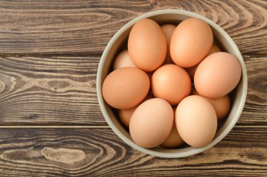 Ahşap arka planda bir kasede çiğ yumurta..