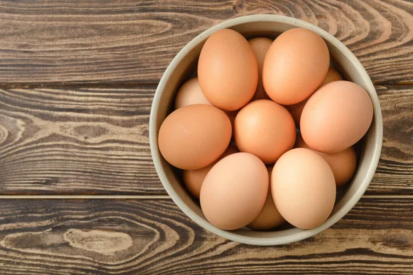 Ahşap arka planda bir kasede çiğ yumurta..