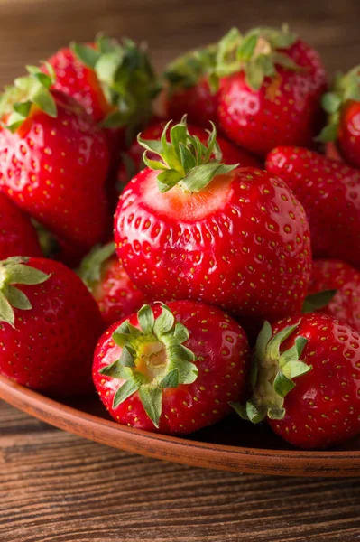 Bir grup kırmızı olgun çilek, ahşap arka planda, yiyecek arka planında.