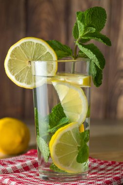 Limonata, limon dilimleri ve cam kaplı nane yaprakları, yemek arkaplanı.