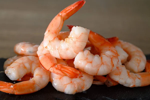 Soyulmuş karidesler, taş kesme tahtası, yiyecek arka planı.