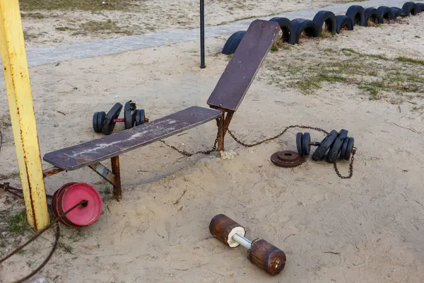 Ev yapımı halter ekipmanlarının olduğu açık hava idman alanı kumlu zeminde halterler ve halterler gibi. Yaratıcı bir fitness alanı.