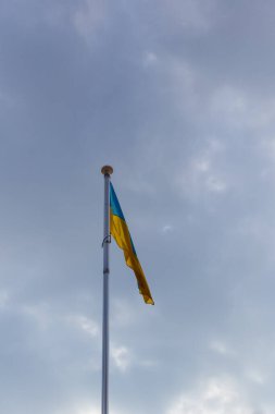 Parçalı bulutlu bir gökyüzüne karşı dalgalanan bir Ukrayna bayrağı, zorlu zamanlarda dayanışma, ulusal gurur ve direnci temsil ediyor..