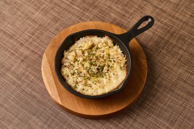 Tahta üzerinde mini tavada peynirli pilav.