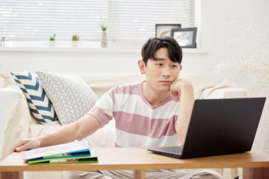 Genç Asyalı Adam Parlak Modern Oturma Odasında Dizüstü bilgisayar ve Klasörlerle Çalışıyor